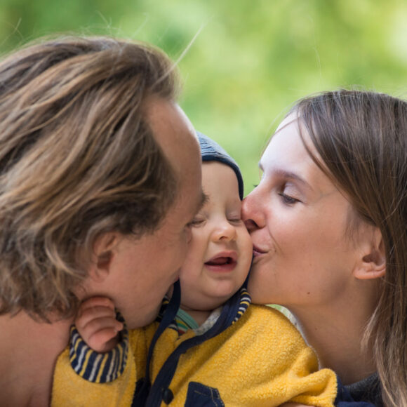 Father and mother kissing their little son