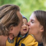 Father and mother kissing their little son