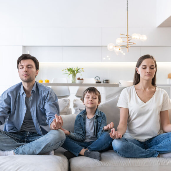 Family sits on the sofa and meditates